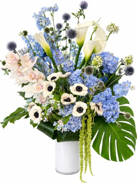 Blue Garden Luxury Bouquet with hydrangeas, calla lilies, anemones, and monstera leaves in a white vase
